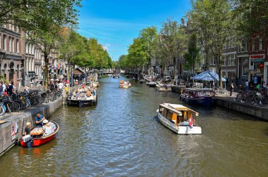 Amsterdam, Hollanda - Ağustos 2022: Kentin kanallarından birinde gezi teknelerini ziyaret edenler