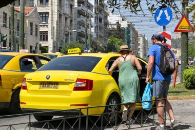 Atina, Yunanistan - Mayıs 2022: Şehir sokaklarından birinde iki kişi sarı taksiye biniyor