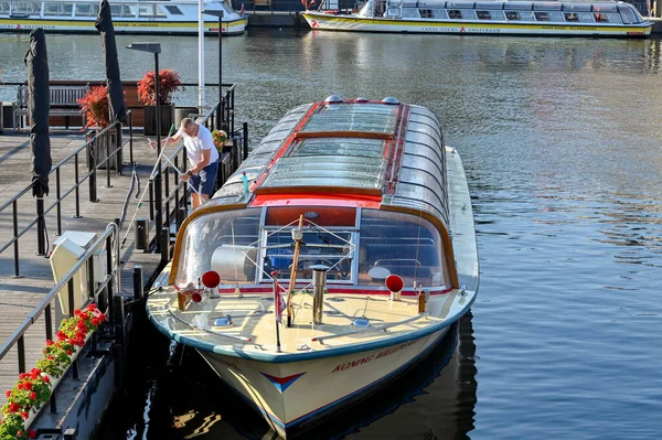アムステルダム オランダ 8月2022 早朝の光の中で観光運河のボートのガラスキャノピーを掃除する人 — ストック写真