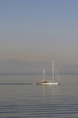 Aegina, Yunanistan - Mayıs 2022: Yelkenli yelkenli sakin bir denizde yavaşça ilerlerken hafif dalgaların oluşturduğu desen.