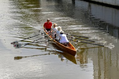 Amsterdam, Hollanda - Ağustos 2022: Olgun kadınlarla birlikte şehir merkezinde bir kanalda egzersiz yapan kayık