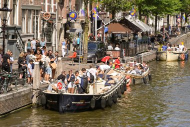 Amsterdam, Hollanda - Ağustos 2022: Turistler şehir merkezinde bir kanal gezisine çıkıyorlar
