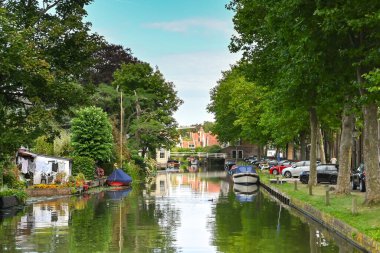 Edam, Hollanda - Ağustos 2022: Hollanda 'nın Edam kentinde peynirleriyle ünlü ağaçlı bir kanalda botlar.