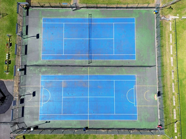 Aerial view of a tennis court alongside a basketball court in a public park. No people.