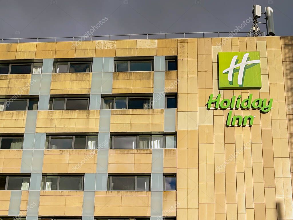 Cardiff, Wales - September 2022: Sign on the outside of the Holiday Inn hotel in Cardiff city centre against a dark stormy sky