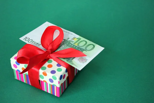 赤い弓でギフトボックスに100ユーロ紙幣 緑の背景 休日や現金の贈り物の概念 ストック写真