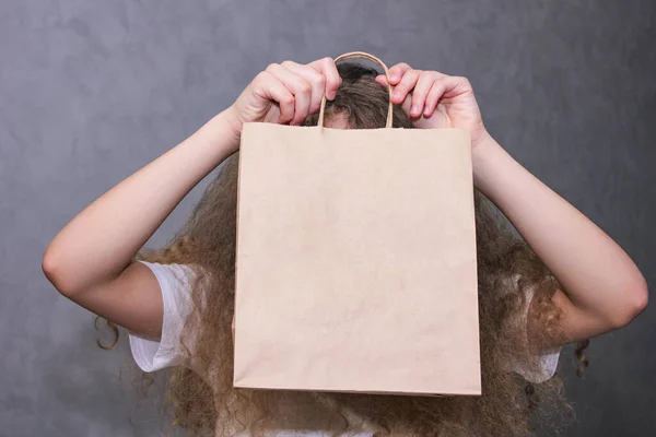 Девушка держит бумажный мешок перед лицом. Лицензионные Стоковые Фото