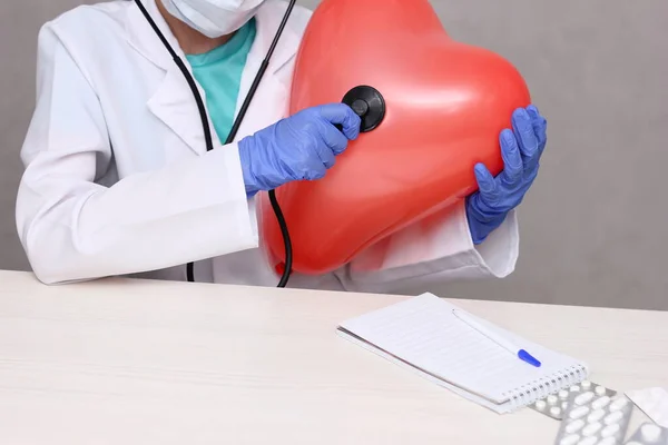 Doctor que escucha un corazón inflable grande con un estetoscopio. —  Fotos de Stock