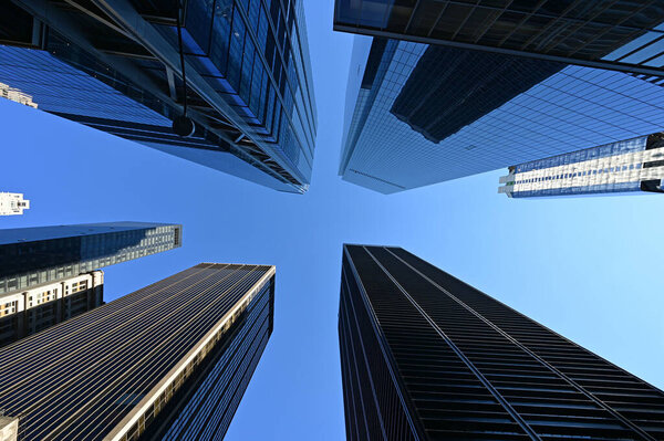 Upward view of skyscrapers in New York City, New York against clear blue sky.