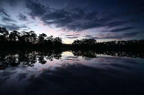 Florida, Everglades Ulusal Parkı 'ndaki sakin gölete yansıyan renkli gün doğumu bulutu.