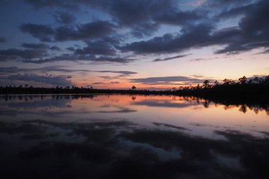 Colorful summer sunset cloudscape over Pine Glades Lake reflected in calm water of Everglades National Park, Florida.