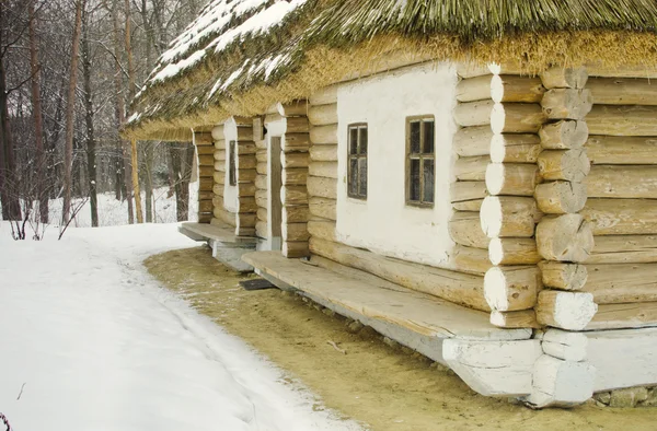 Старая деревянная хижина, покрытая соломой в снегу — стоковое фото