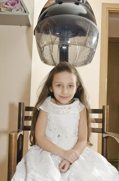 Menina bonita nova está sentada na cadeira no cabeleireiro — Fotografia de Stock