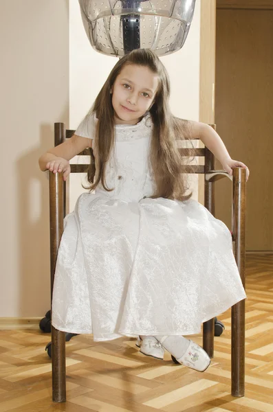 Menina bonita nova está sentada na cadeira no cabeleireiro — Fotografia de Stock