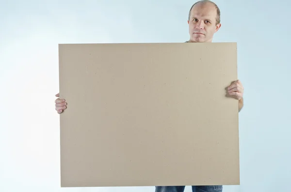Portrait of man holding empty table to put words on blue backgro — Stock Photo, Image