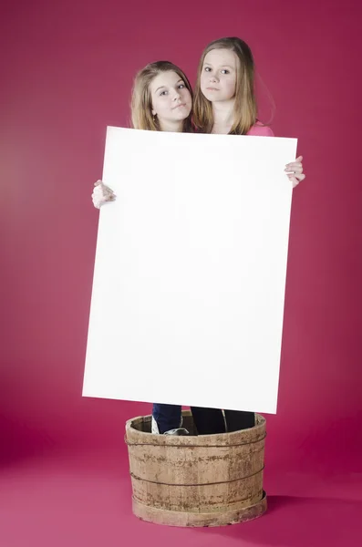 Portrait of girls standing in barrel and holding empty poster — Stock Photo, Image