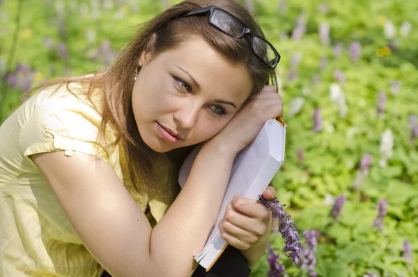 Ritratto di bella ragazza con libro e occhiali nei fronti primaverili — Foto Stock