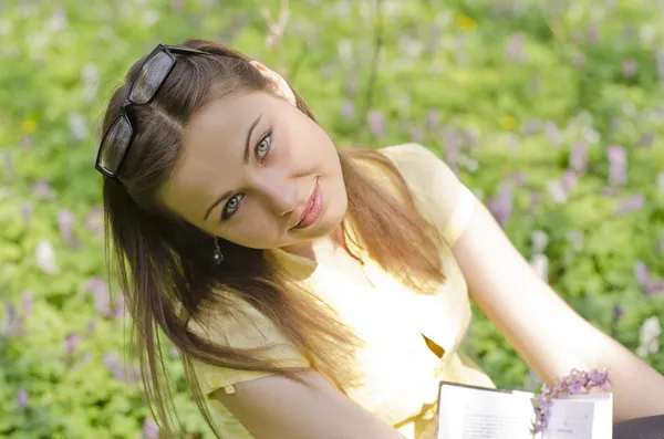 Portrait of beautiful girl with book and glasses in spring fore — Stock Photo, Image