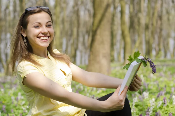 Portret van mooi lachende meisje met boek en bril in spri — Stockfoto