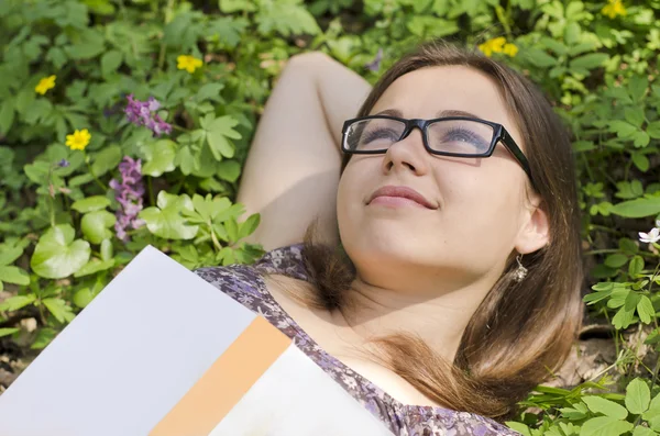 Ritratto di bella ragazza con libro e bicchieri tra le erbe — Foto Stock