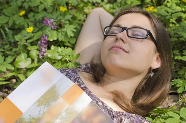 Ritratto di bella ragazza con libro e bicchieri tra le erbe — Foto Stock