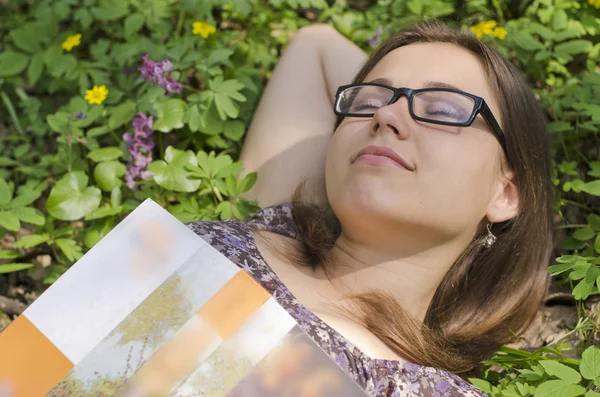 Portrait of beautiful girl with book and glasses among herbs — Stock Photo, Image