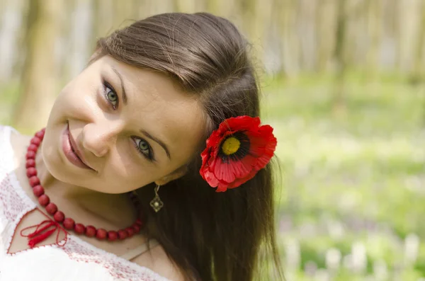 Retrato de hermosa chica sonriente con flor de amapola en el pelo — Foto de Stock