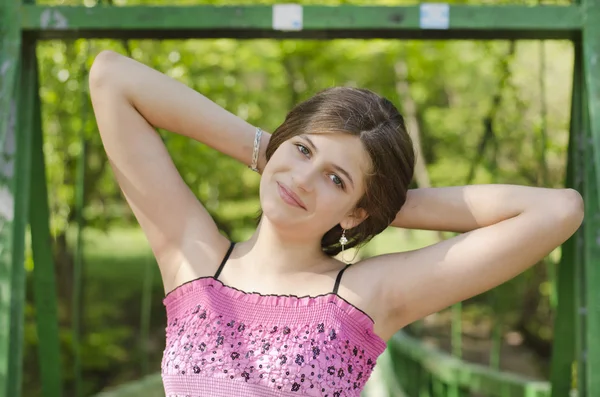 Portret pięknej dziewczyny uśmiechający się w parku naprzeciwko mostu — Zdjęcie stockowe