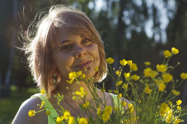 Schönes lächelndes Mädchen hält Blume (Butterblume) im Sonnenuntergang — Stockfoto