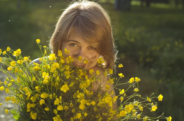 Vacker flicka håller blomma (smörblomma) i solnedgången ljus — Stockfoto