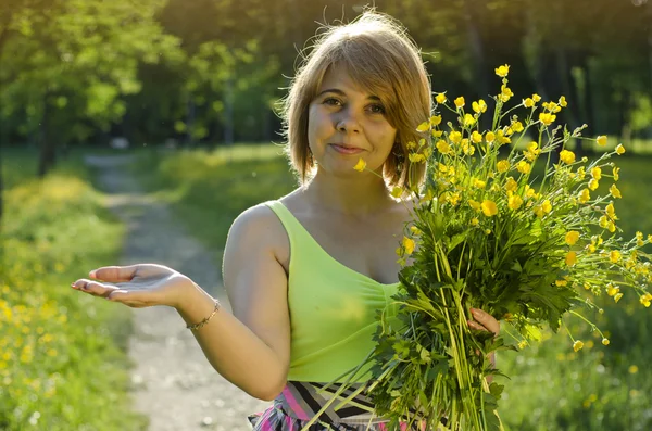 Vacker flicka håller blomma (smörblomma) i solnedgången ljus — Stockfoto