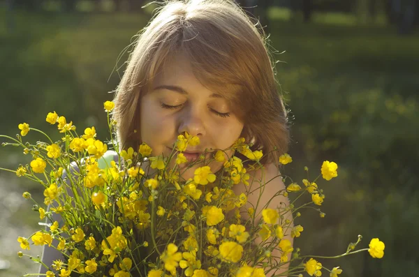 Menina bonita está segurando flor (buttercup) em luz do pôr do sol — Fotografia de Stock
