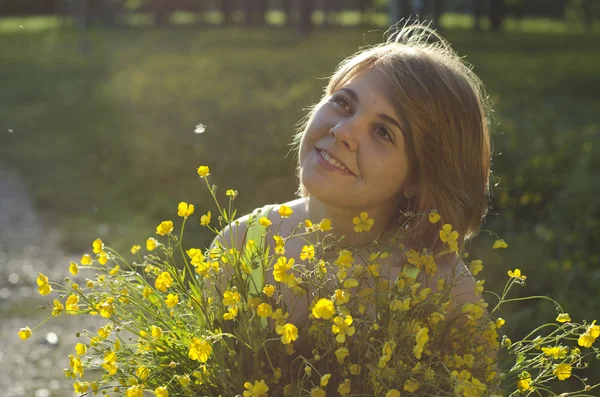 Красива дівчина тримає квітку (масляну чашку) під час заходу сонця — стокове фото