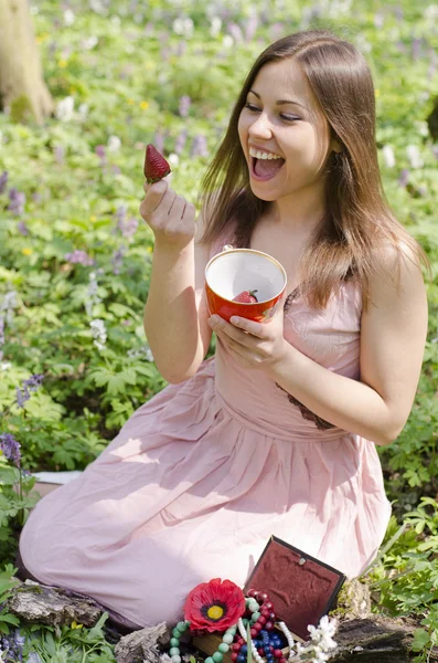 Beautiful smiling girl is holding cup with strawberries — Stock Photo, Image