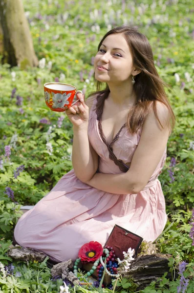 Hermosa chica sonriente está sosteniendo taza roja ornamentada — Foto de Stock