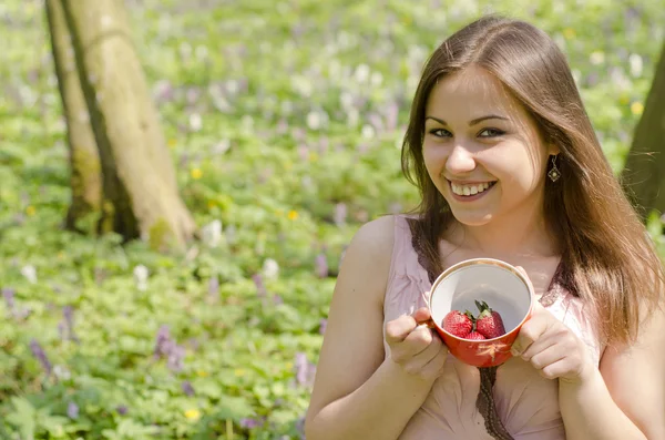Beautiful smiling girl is holding cup with strawberries Stock Picture