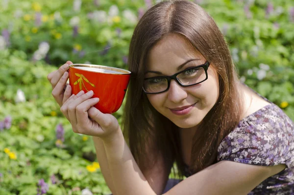 Uśmiechający się piękna dziewczyna w okularach trzyma kubek czerwony — Zdjęcie stockowe
