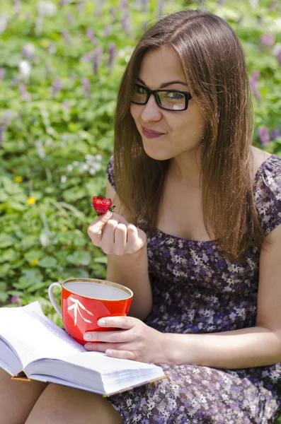 Sorridente bella ragazza in occhiali sta mangiando fragola — Foto Stock