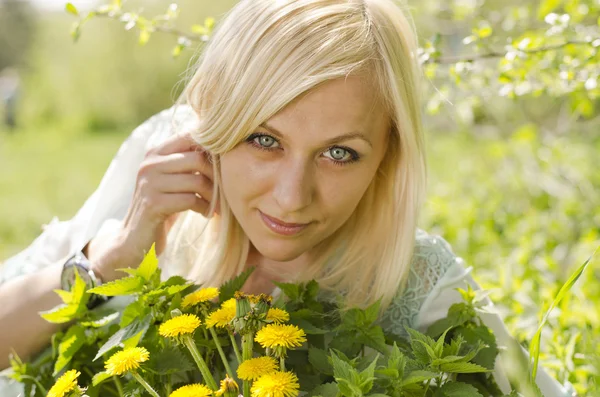 Portret piękne blondynka z mniszka lekarskiego w parku — Zdjęcie stockowe