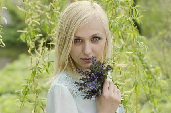 Portrait of beautiful blonde girl with lungwort flowers on willo — Stock Photo, Image