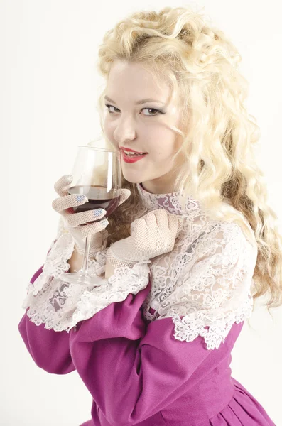 Studio portrait of a beautiful, attractive and smiling girl dressed like an old fashionable lady with a glass of red wine on white background — Stock Photo, Image