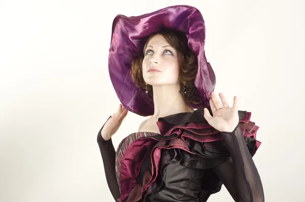 Studio portrait of an attractive, beautiful woman in wide hat dressed in old fashinable style — Stock Photo, Image