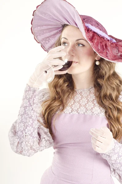 Studio portret van mooie vrouw gekleed in oude fashinable stijl en een brede hoed met een glas wijn — Stockfoto