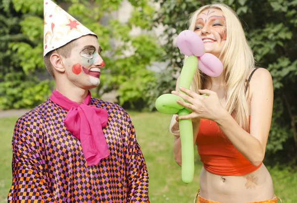 Retrato de un hombre sonriente vestido como un payaso presentó un globo a una chica feliz con maquillaje de mariposa —  Fotos de Stock