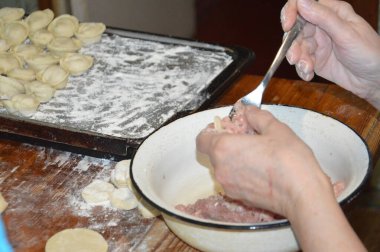 Kadın evde mantı heykeli yapıyor.
