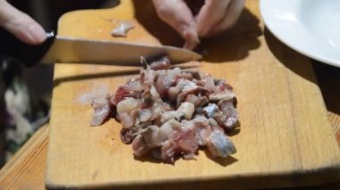 Mutfak tahtasındaki bıçakla ringa balığı dilimlemek.