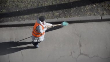 Özel takım elbiseli bir hademe caddeyi süpürgeyle süpürüyor.