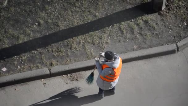 一个穿着特殊西服的女看门人用扫帚扫街 — 图库视频影像