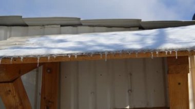 Evin çatısında buzdan buz saçakları asılı duruyor.