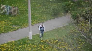 Yaşlı bir adam bahçede bir benzin makası biçiyor.